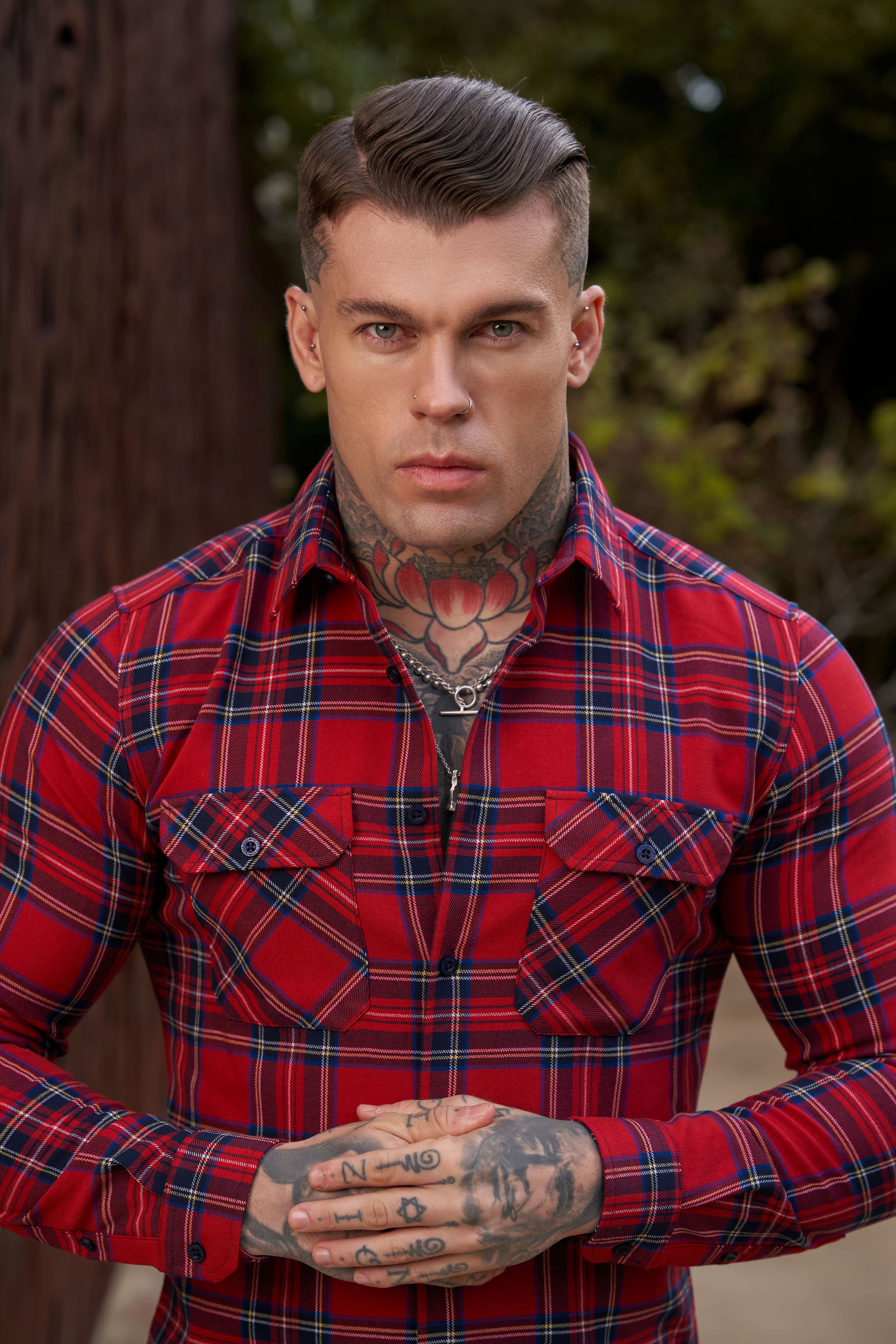 A man wearing a red tartan checkered shirt with double pockets.