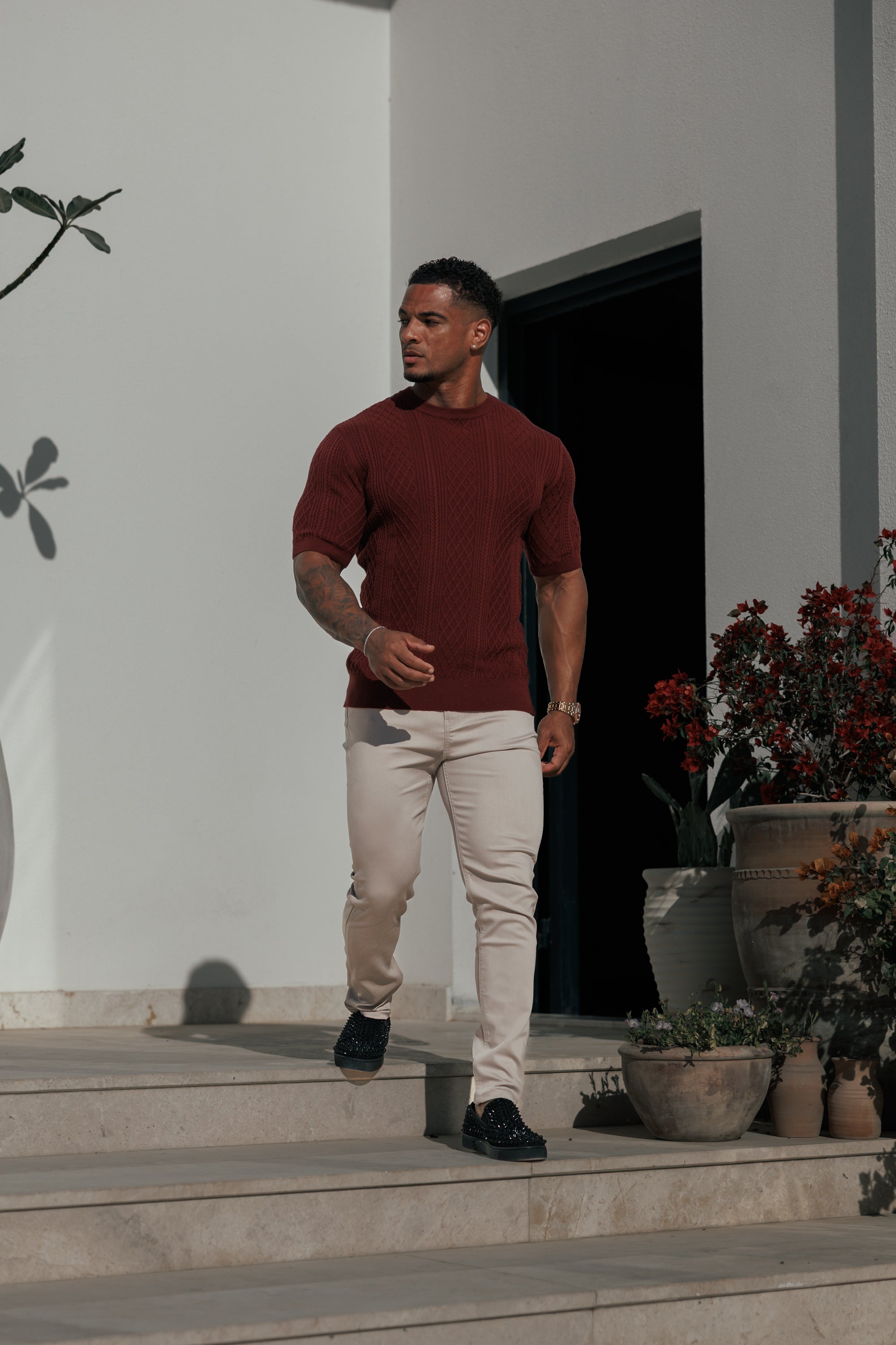 Man standing on steps outside a building with plants around