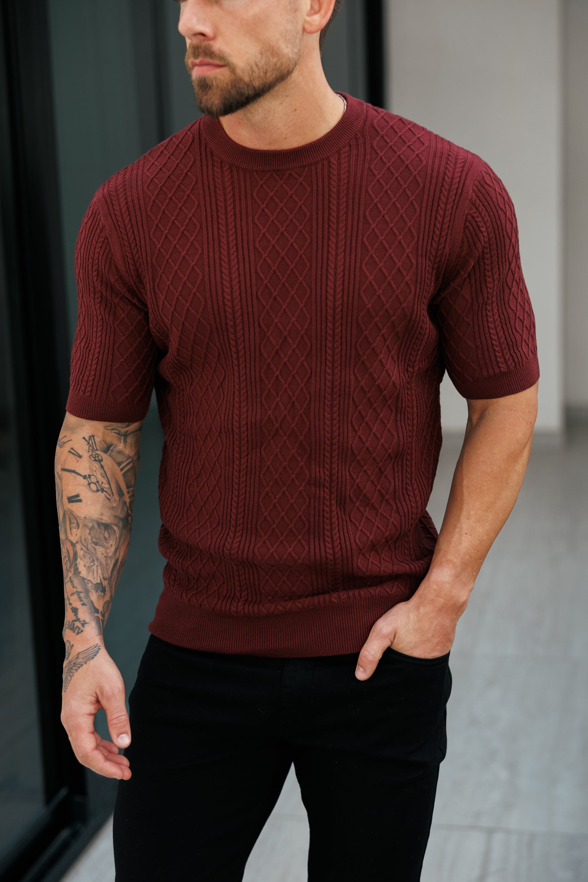 Man wearing a maroon knitted sweater with a blurred background