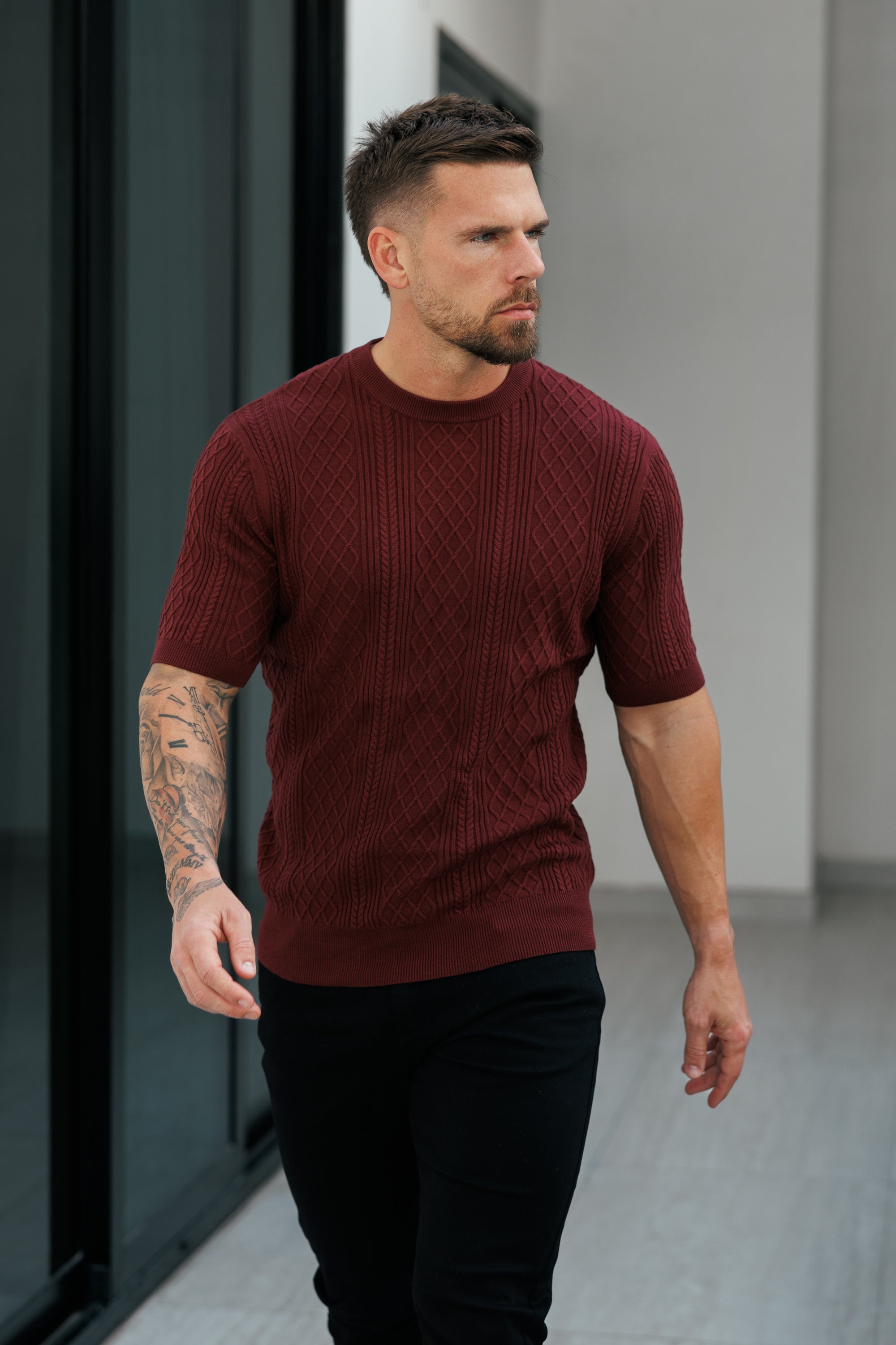 Man wearing a maroon sweater walking outdoors.