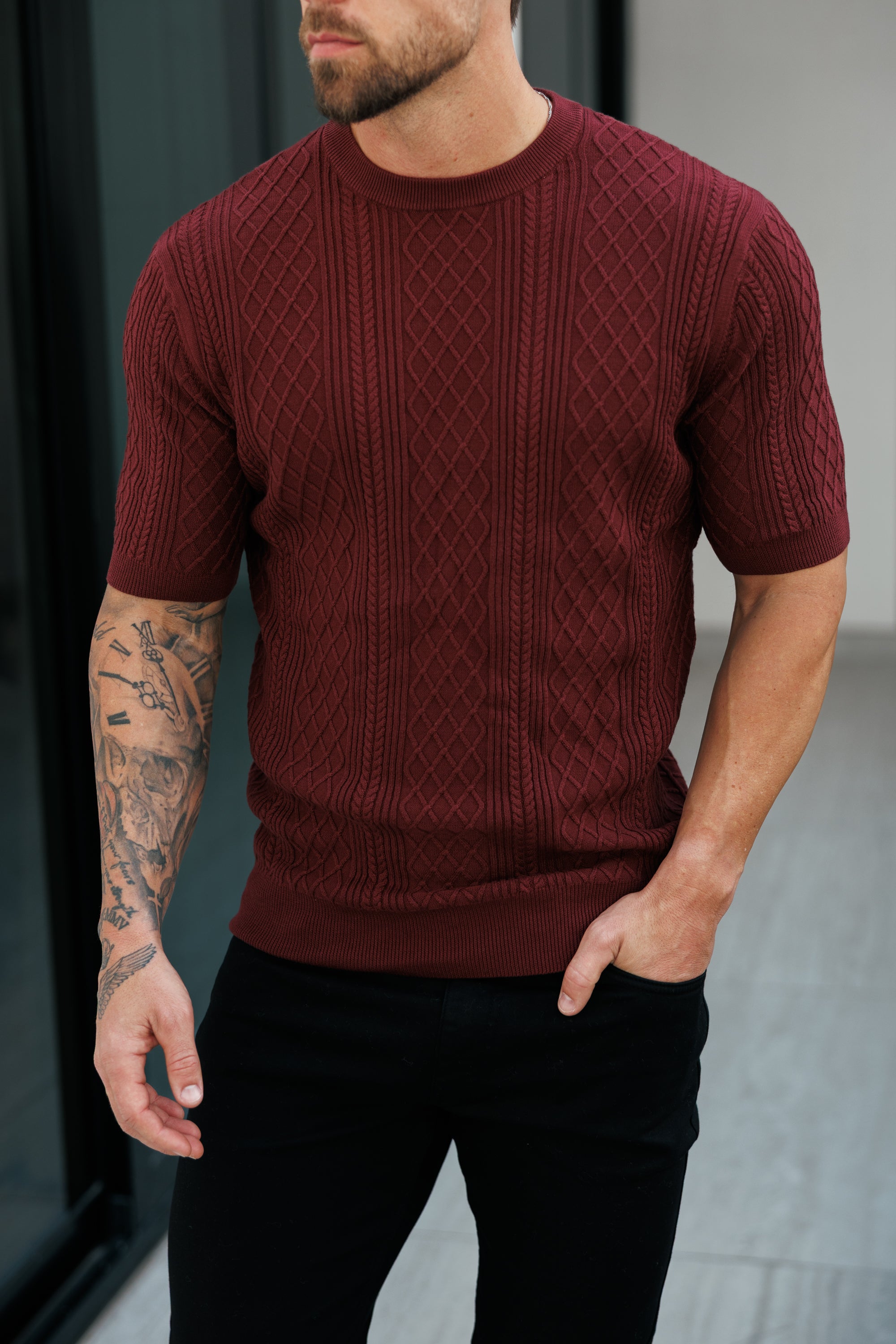 Man wearing a maroon knitted sweater with a blurred background