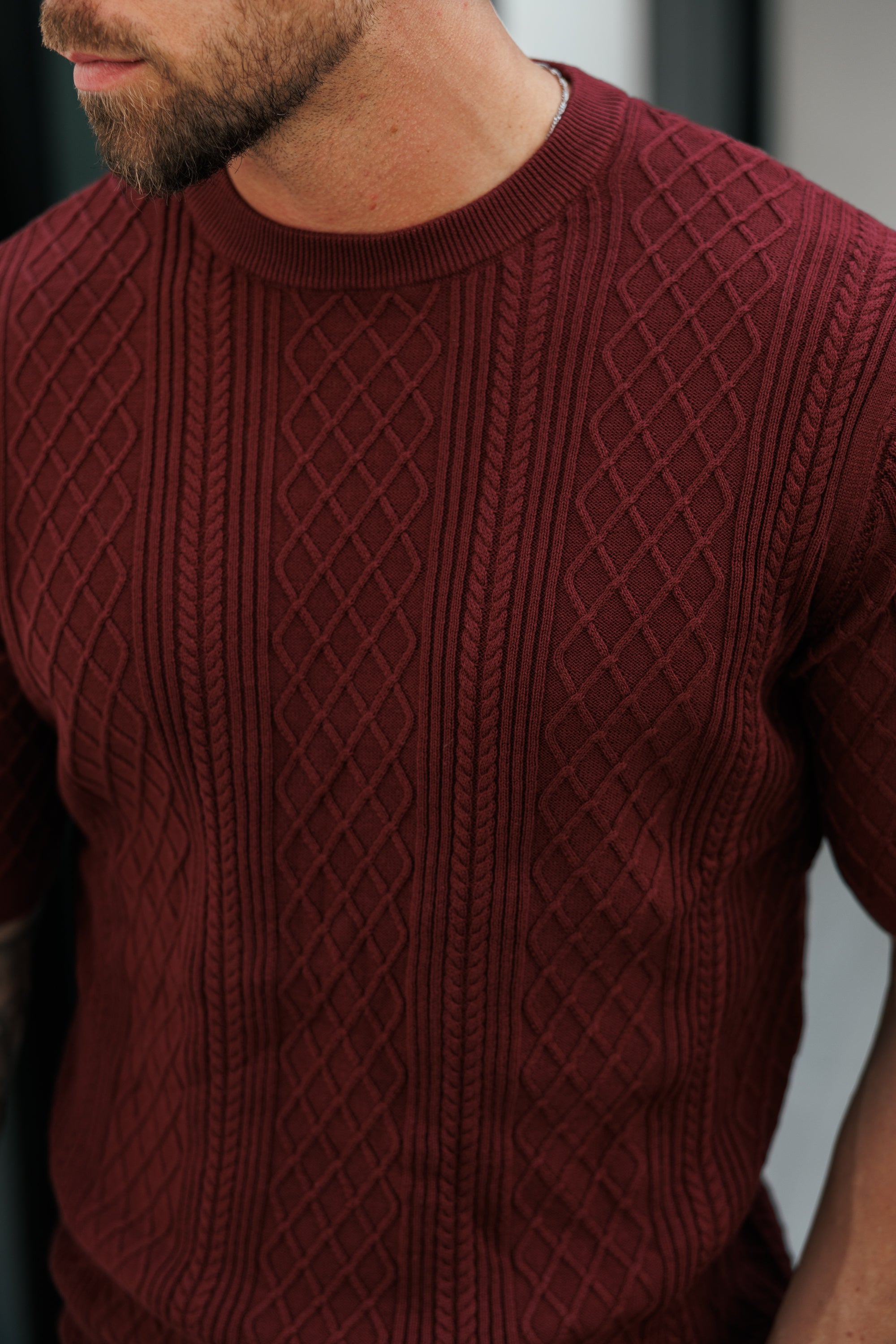 Close-up of a person wearing a maroon cable knit sweater.